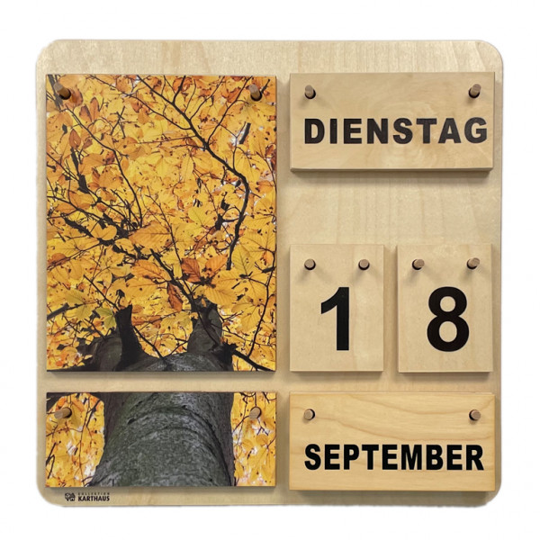 Holzkalender mit wechselbaren Plättchen für Wochentage, Datum, Monat und Jahreszeit. Zwei Naturfotos, die zusammen ein Gesamtbild ergeben. Baum mit gelben Blättern, von unten fotografiert