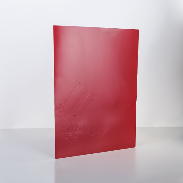 Rote Pressemappe mit geprägtem Design und dem Slogan „Da sein, leben helfen“