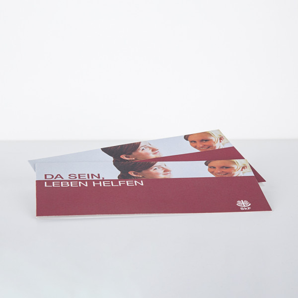 Zwei Klappkarten mit dem Text DA SEIN, LEBEN HELFEN und jeweils zwei Frauen darauf