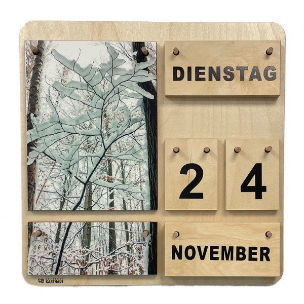 Holzkalender mit wechselbaren Plättchen für Wochentage, Datum, Monat und Jahreszeit. Zwei Naturfotos, die zusammen ein Gesamtbild ergeben. Verschneite Bäume und Äste, von unten fotografiert